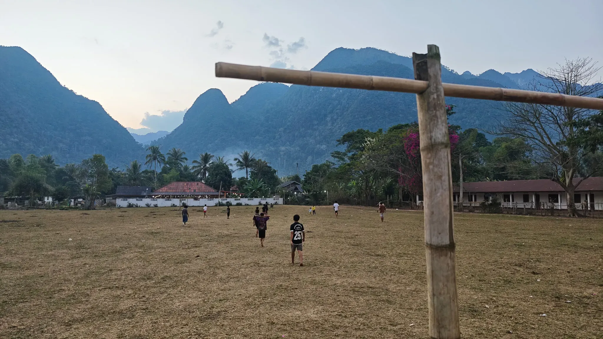 Kids playing football beneath karst mountains at Muang Ngoi