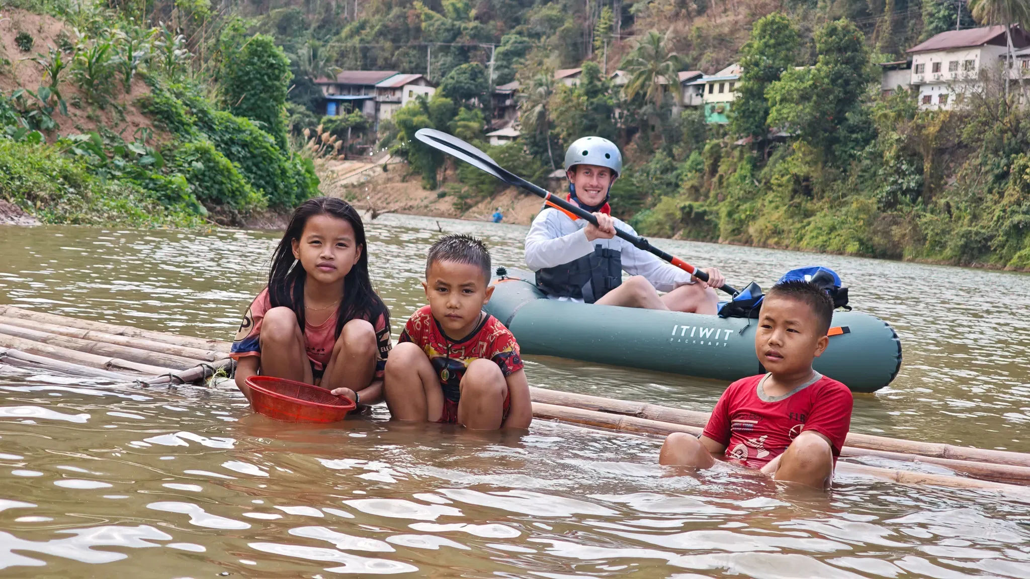 Lao kids on a bamboo raft beside a packraft at Muang Khua