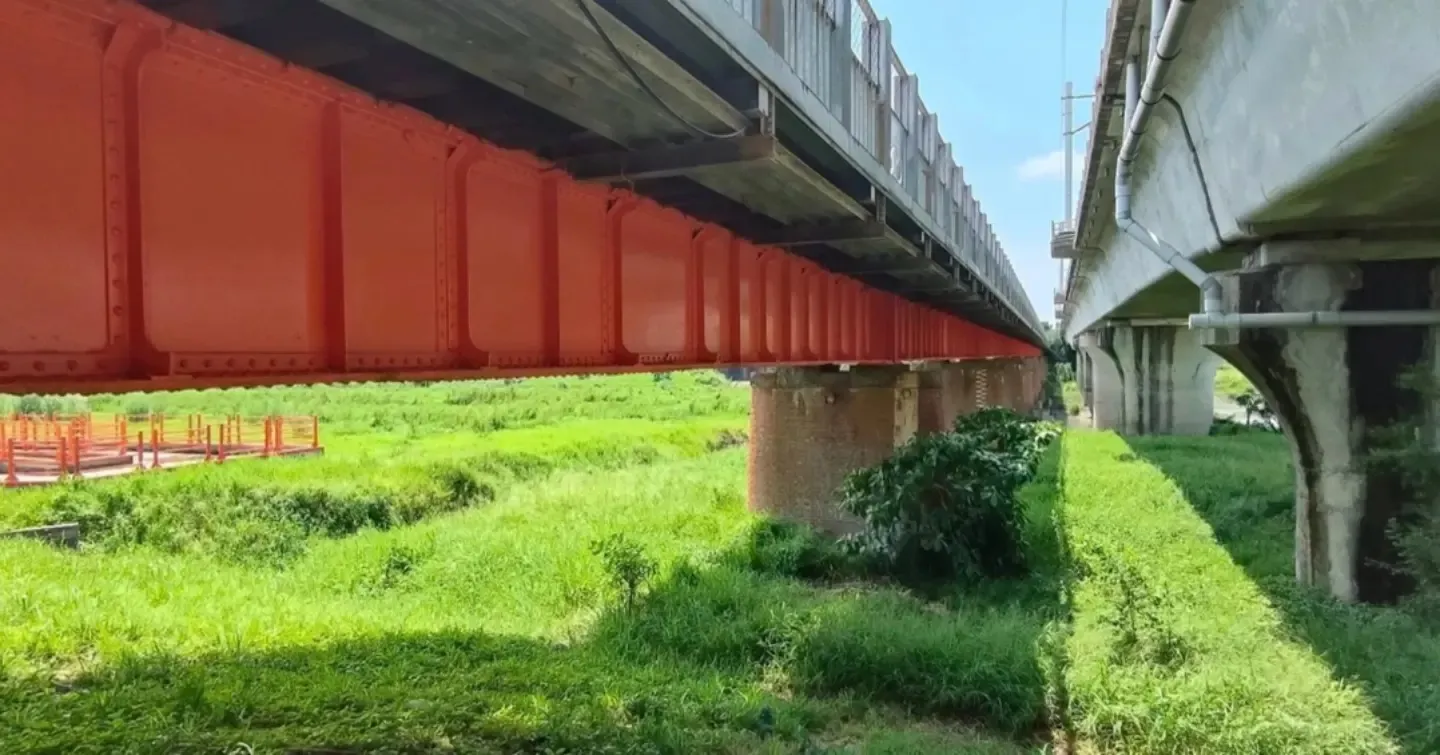 The old red railway bridge from underneath, with green grass below